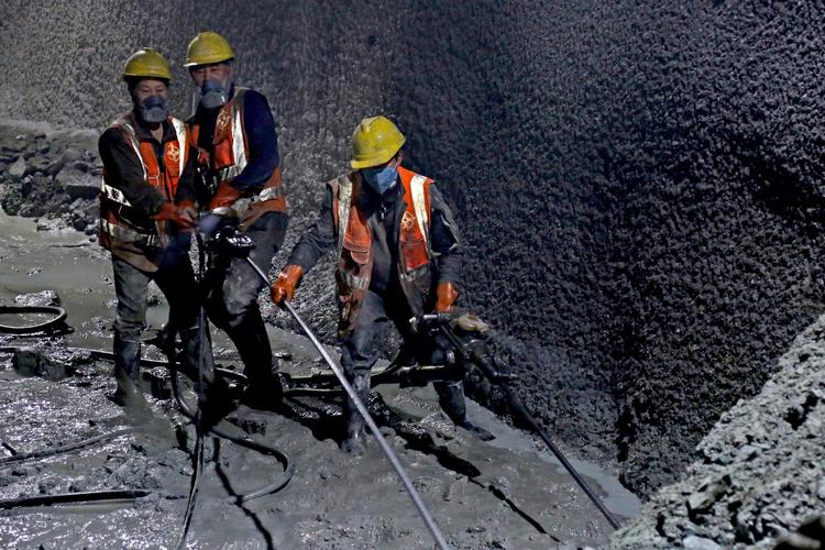 在新疆哈密g575公路东天山特长隧道,中交一公局工人操作钻机钻动岩石